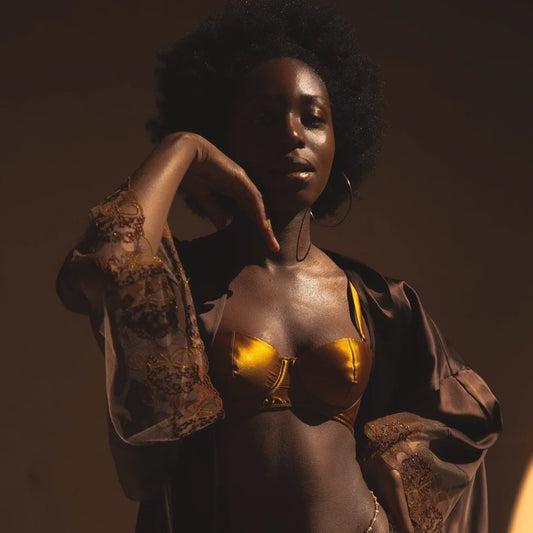Model wearing gold satin bra and brown lace robe